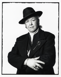 108344 Portret van een vrouw met een hoed op en een tennis-broche op de revers van haar jas.